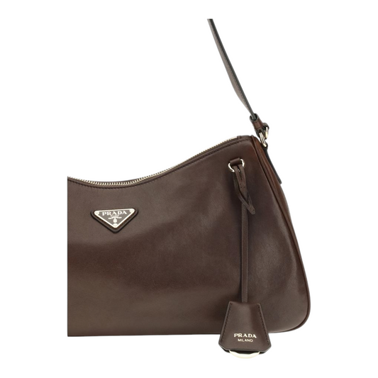 Bolso de hombro Prada Aimée en piel marrón con logo triangular esmaltado y detalles metálicos de XT & Co