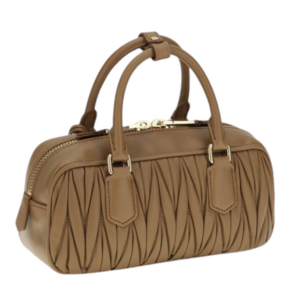 Bolso Arcadie de XT & Co en piel napa beige con diseño matelassé, asas tubulares y placa con monograma metálico.