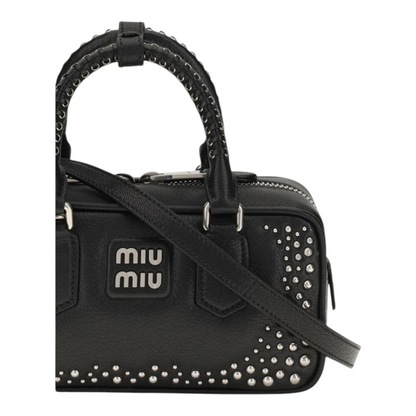 Bolso Arcadie de XT & Co en piel negra con tachuelas plateadas, asas superiores y logotipo metálico frontal.