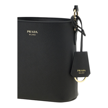 Bolso mini bucket Prada de piel Saffiano negra con logo metálico dorado, disponible en XT & Co
