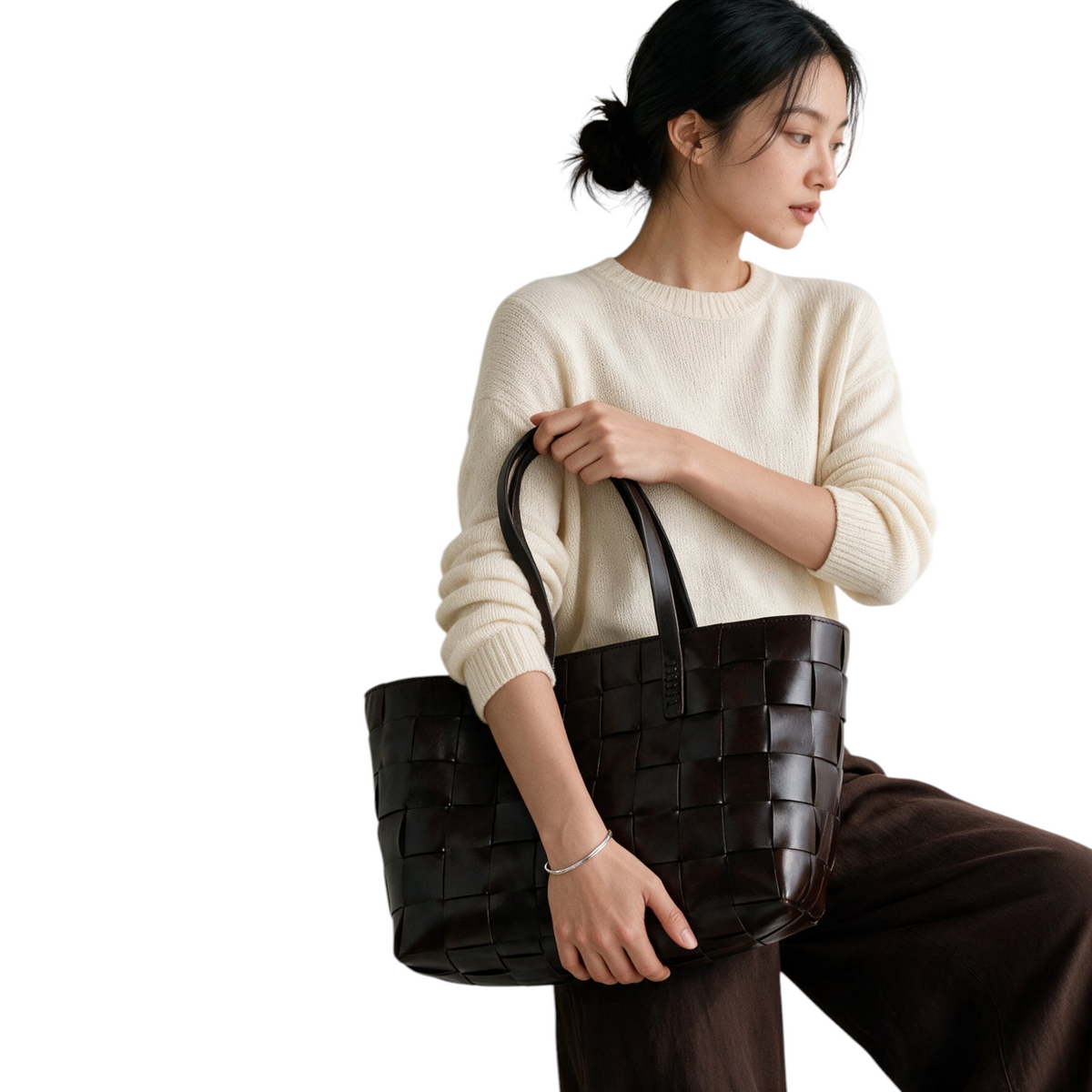 XT & Co Dragon Diffusion Japan Tote en cuero marrón trenzado con asas planas, sostenido por una modelo.