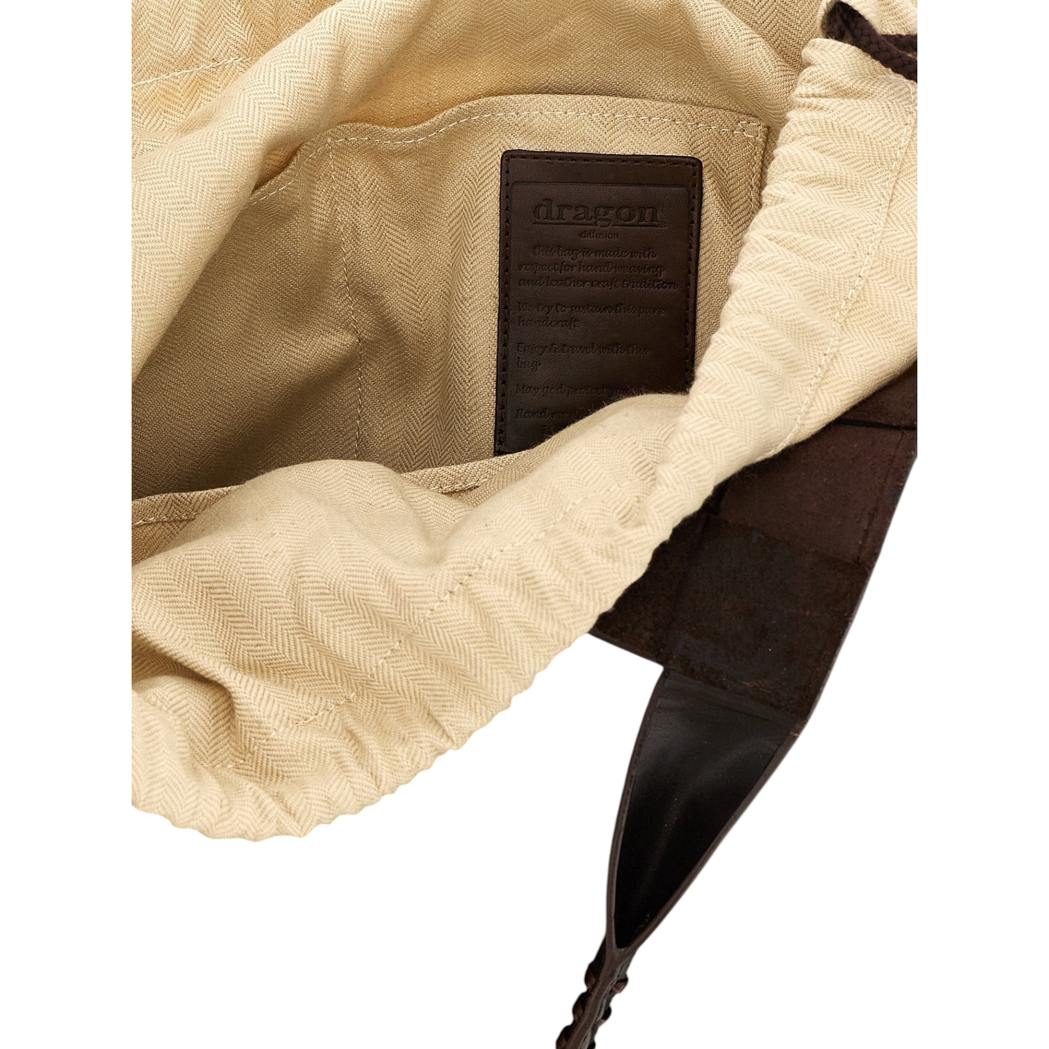 Interior del bolso Dragon Diffusion Castello de XT & Co con forro de lona beige y etiqueta de cuero marrón grabada